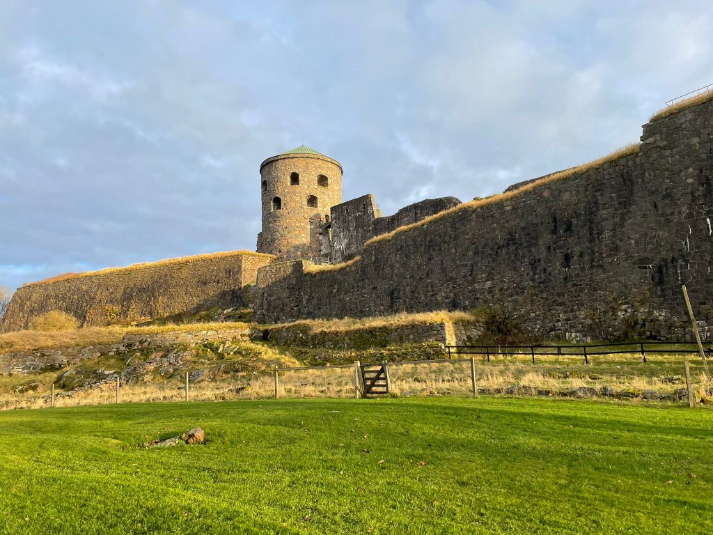 Stone walls and round tower of Bohus Fortress in Kungälv, lit by pale afternoon light.