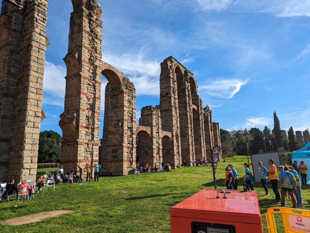 Locals enjoying a sunny day at the Acueducto de los Milagros, a must-see Roman ruin in Mérida, Spain for a first-time visitors
