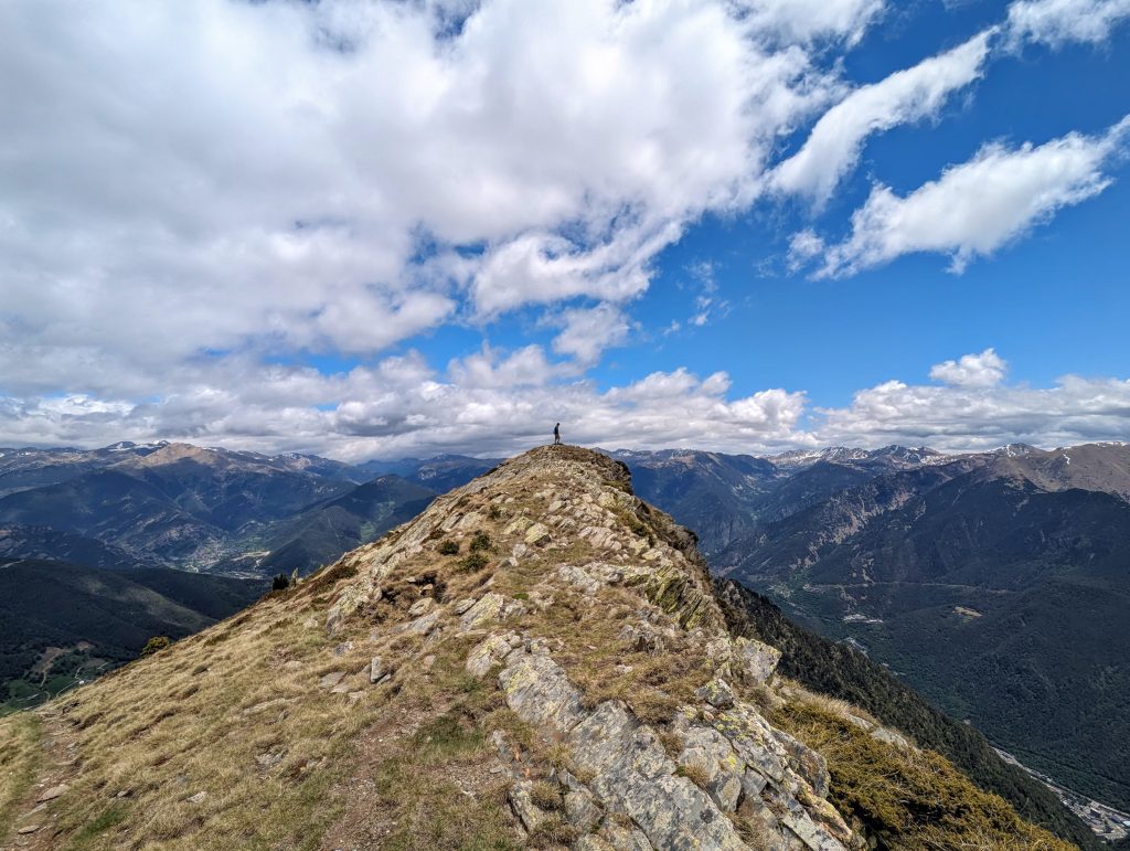 Garrett Landers standing on a mountain peak with a view of valleys and distant peaks