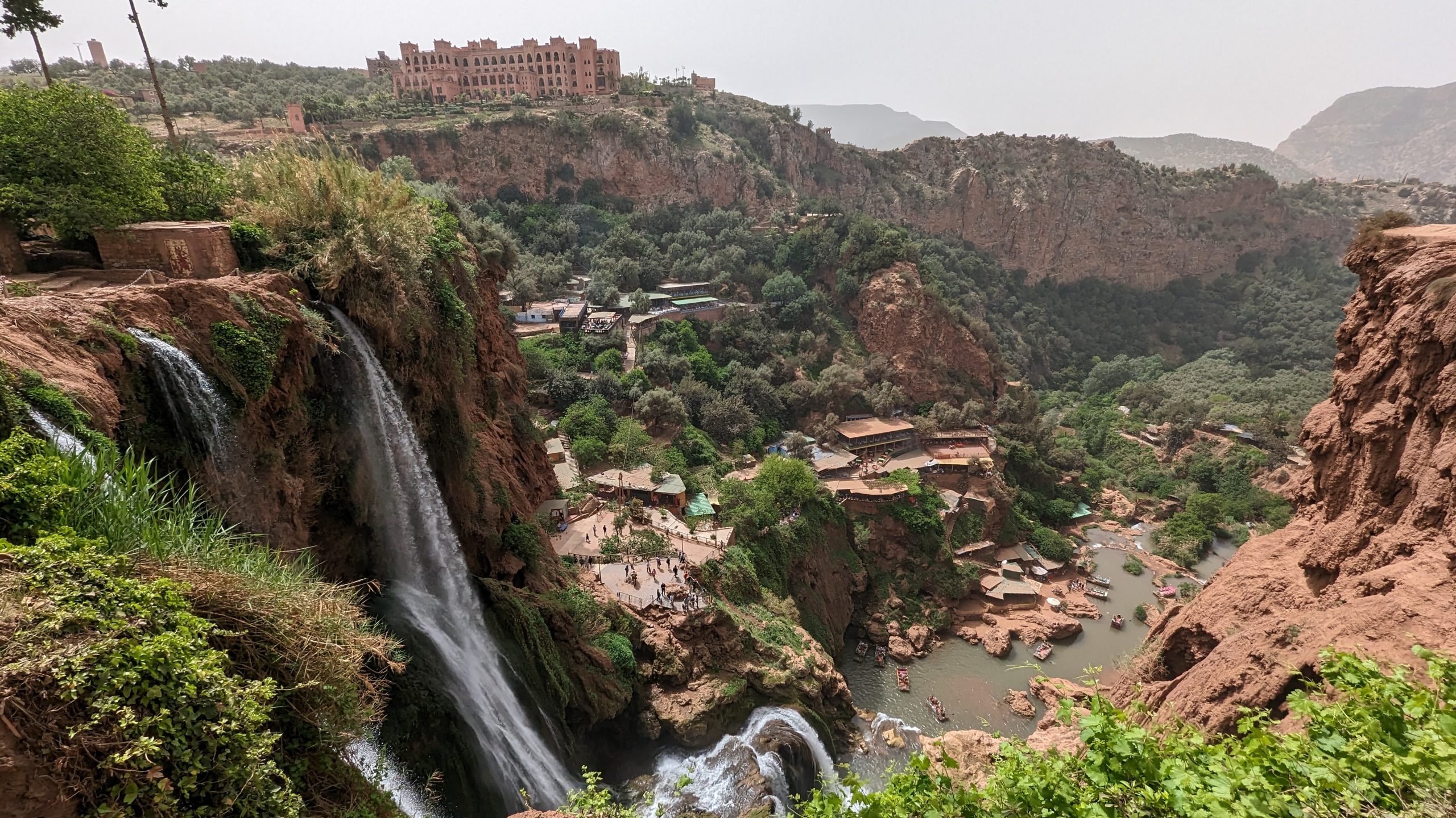 Aerial view of Ouzoud Waterfalls and riverside cafés below.