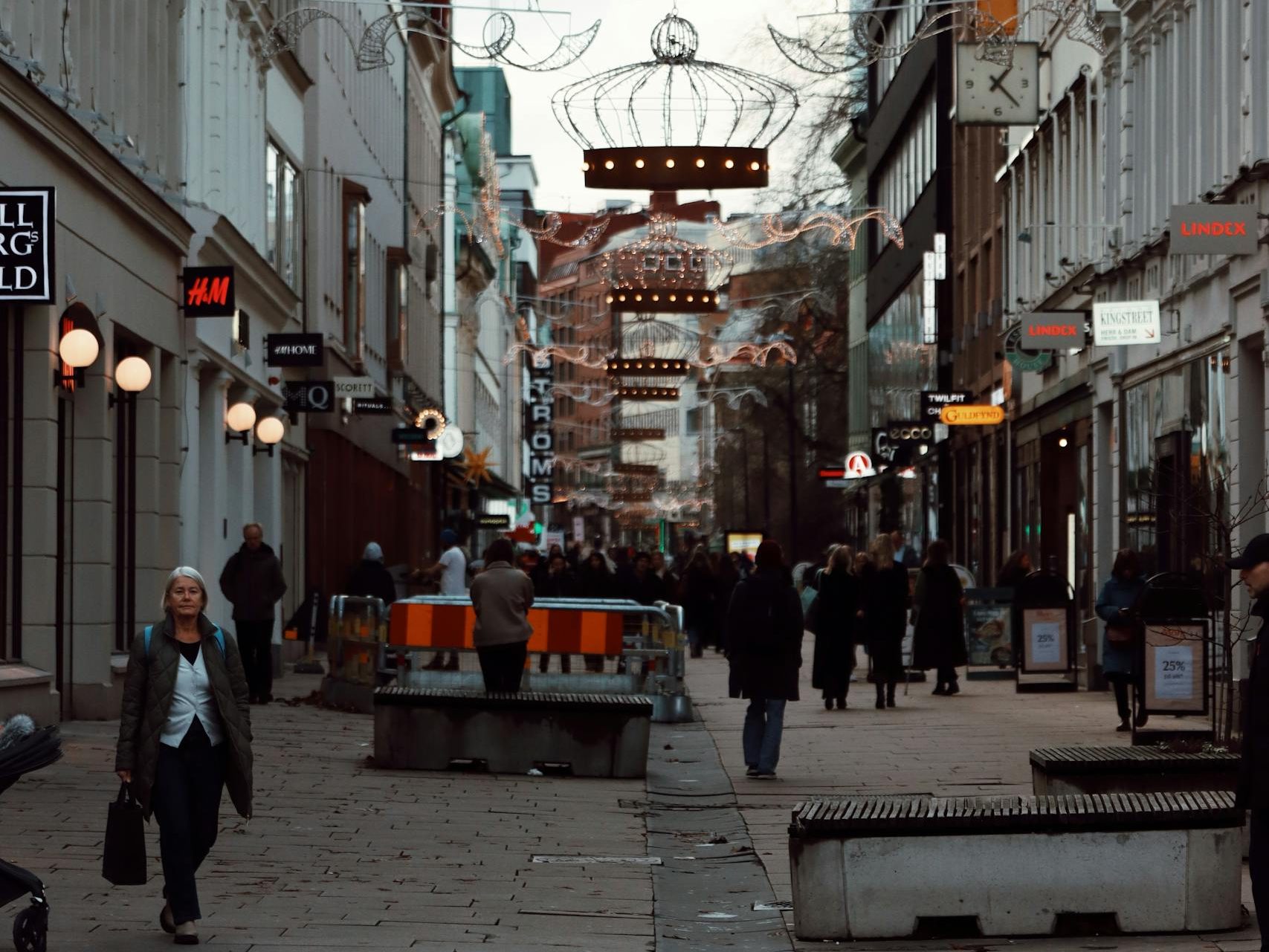 Urban street scene in Gothenburg, Sweden with festive light decorations and bustling pedestrians.