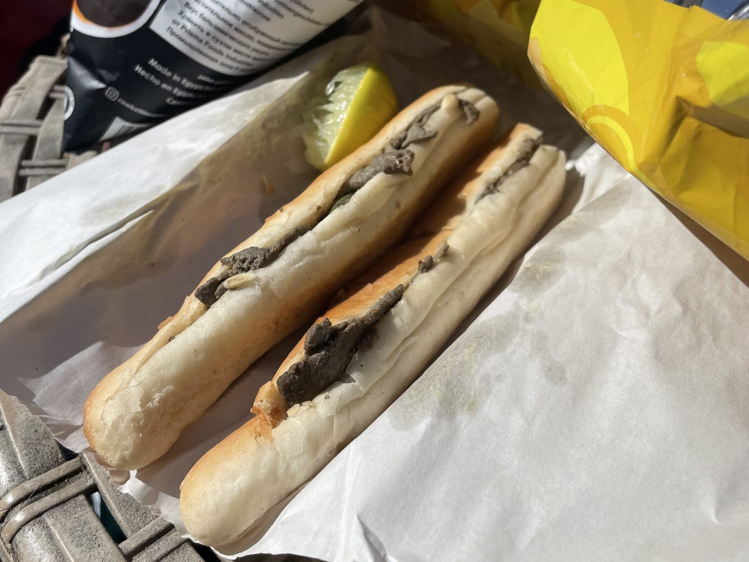 Close-up of Alexandrian-style liver sandwiches with lemon wedge and snack chips.