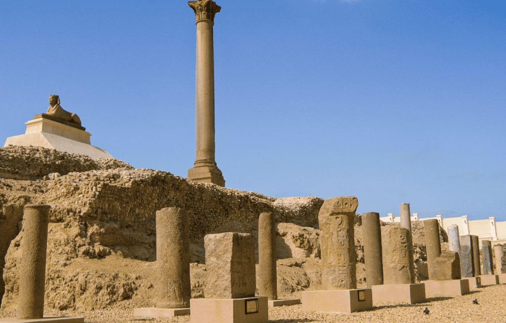 Pompey’s Pillar in Alexandria rising over the ruins of the Serapeum under a clear blue sky.