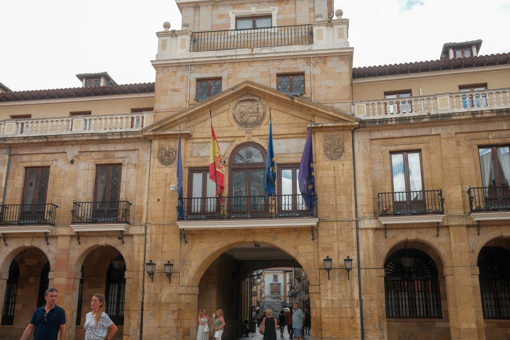 Town Hall of Oviedo, Asturias, Spain, with Spanish, Asturian, and EU flags displayed on the historic facade.