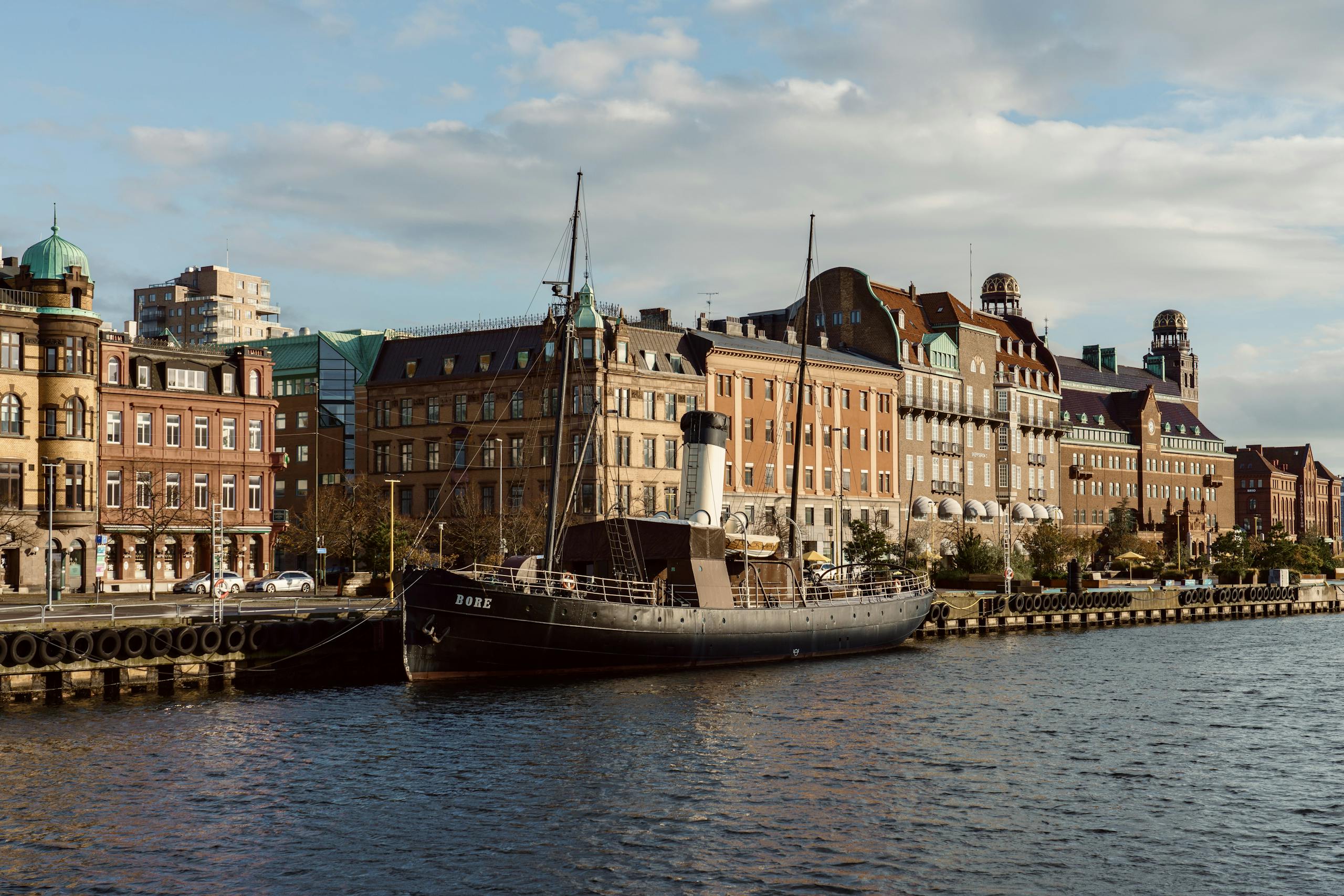 Historic steamship docked along waterfront with picturesque buildings in Malmö.