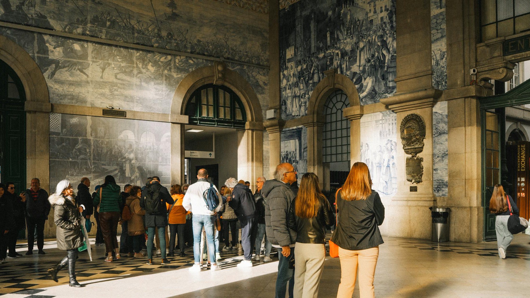 Visitors exploring the iconic São Bento Station showcasing beautiful azulejos in Porto, Portugal.