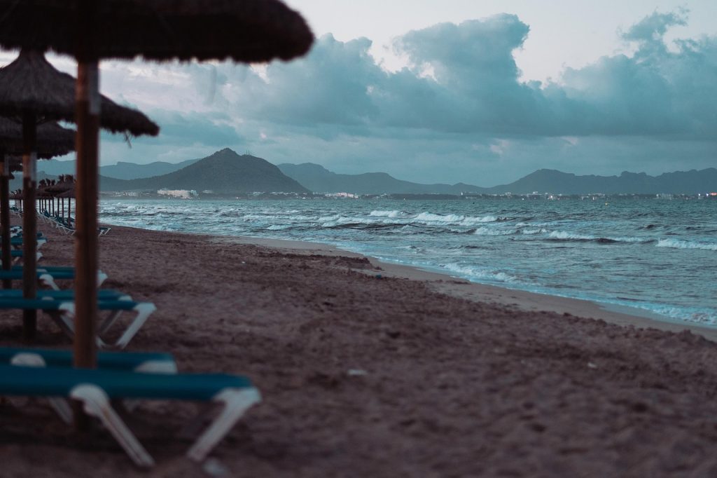 Empty loungers on Can Picafort beach in Alcúdia Bay, Mallorca, under cloudy April skies