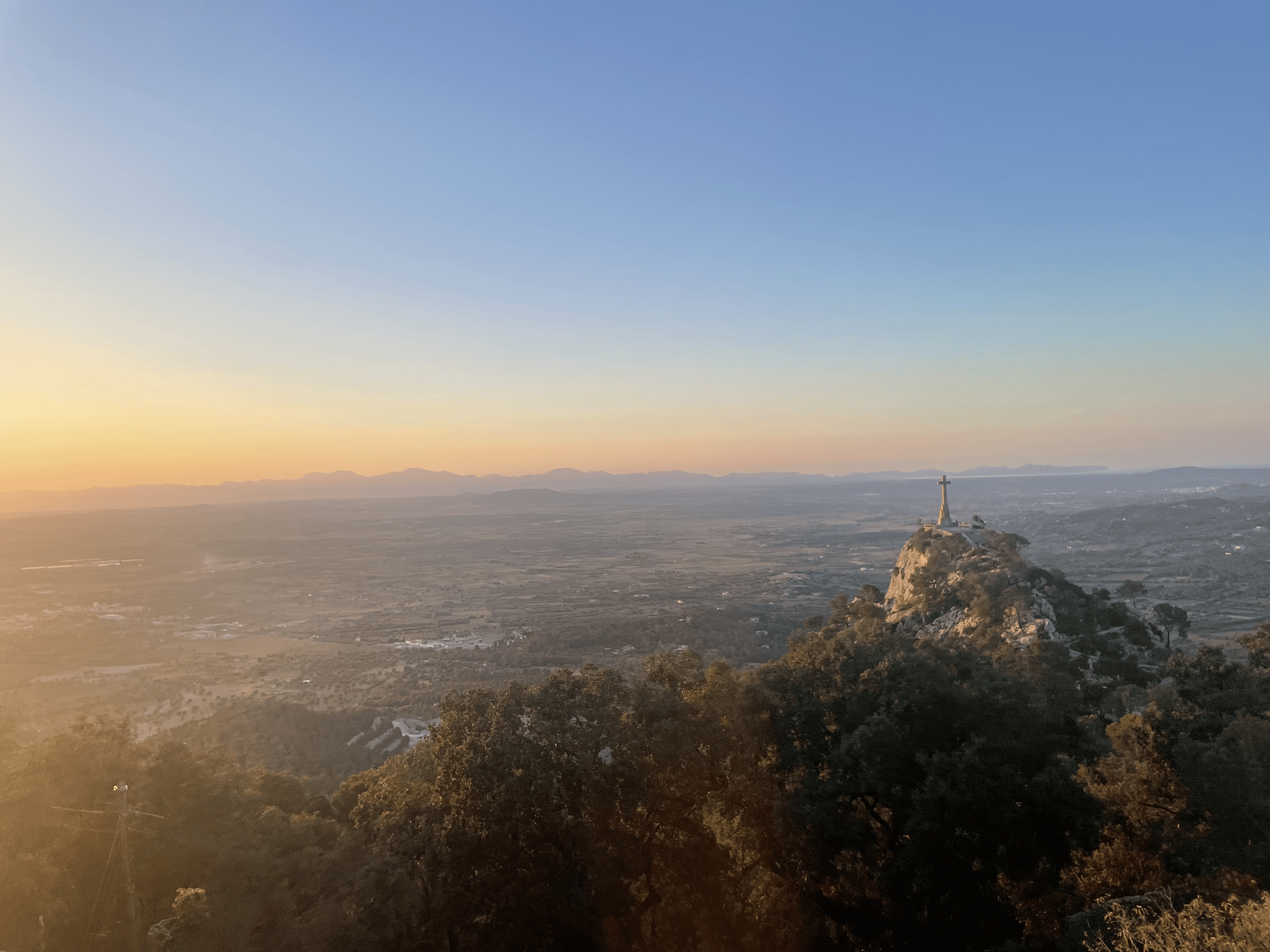 Sunset view from Sant Salvador Monastery in Felanitx, Mallorca, with cross monument on a hill.