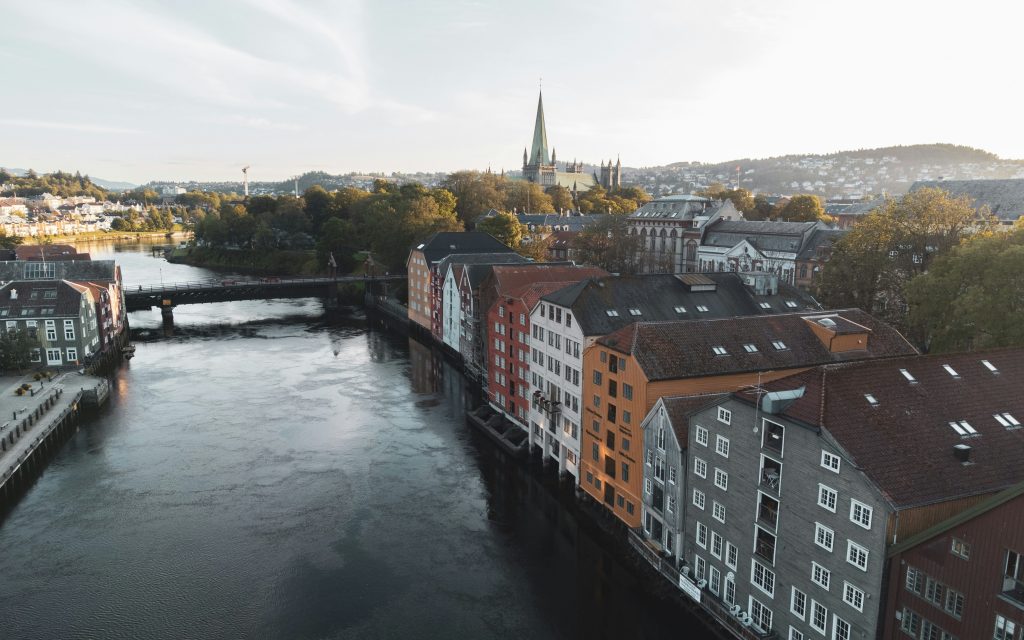 Colorful wooden warehouses along the Nidelva River in Trondheim’s Bakklandet district during soft morning light.