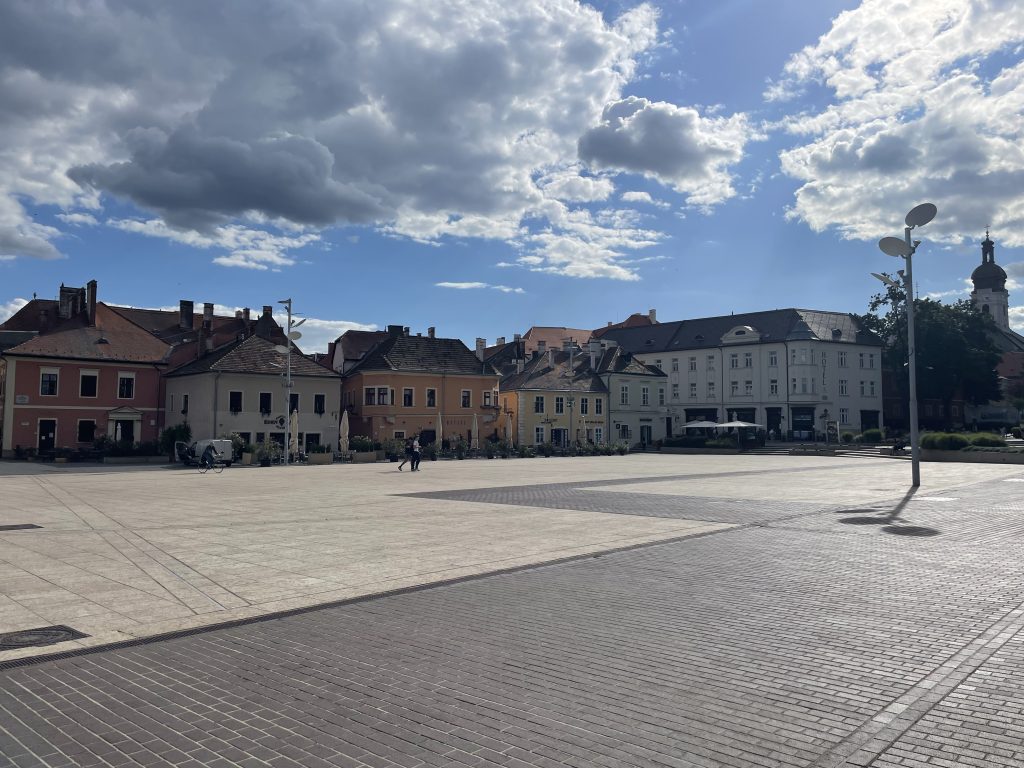 Colorful historic houses around Bécsi kapu Square in Győr, Hungary, under a bright afternoon sky.
