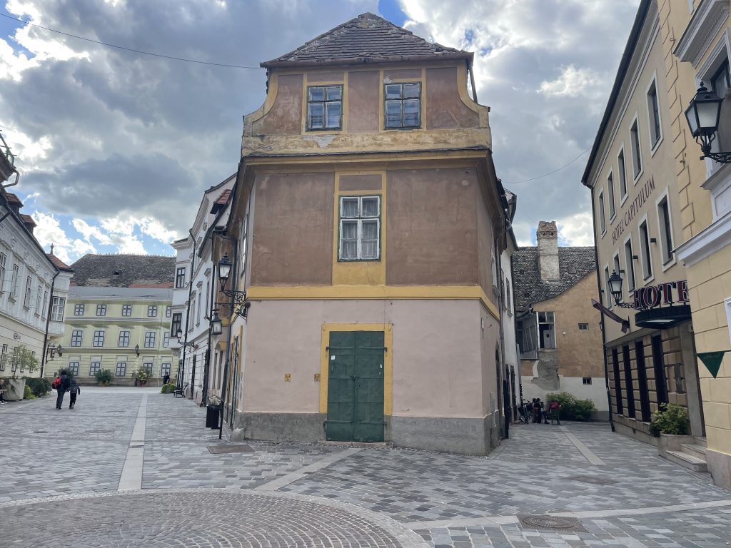 Historic corner building in Győr’s Old Town, Hungary, with pastel facades and cobblestone streets near Hotel Capitulum.