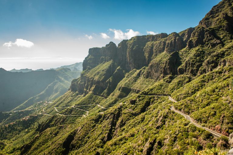 Winding mountain road through Masca Valley in northern Tenerife in November, surrounded by dramatic green cliffs under a clear blue sky