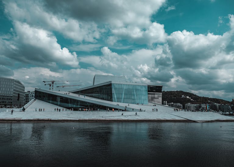 The modern Opera House pictured in Oslo in September with dramatic clouds and waterfront reflection in Oslo, Norway.