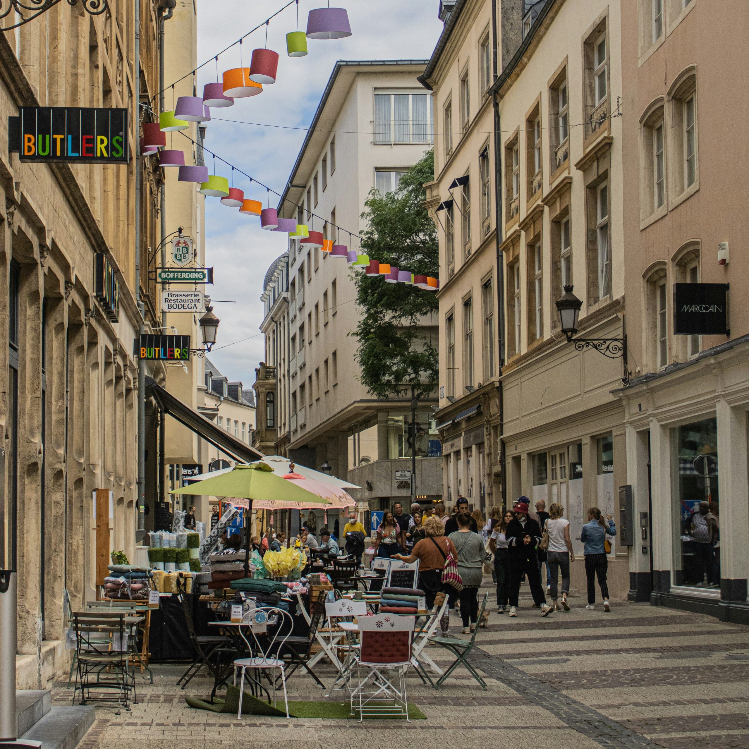 Pedestrian street in Luxembourg City with cafés, shops, and colorful hanging lanterns