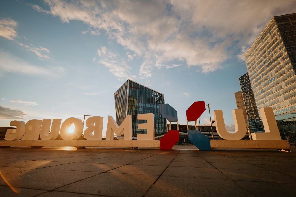 Luxembourg City sign in the Kirchberg district with modern buildings at sunset
