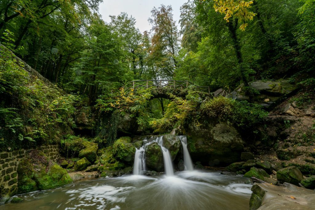 Schiessentümpel Waterfall in the Mullerthal region of Luxembourg with the stone footbridge above
