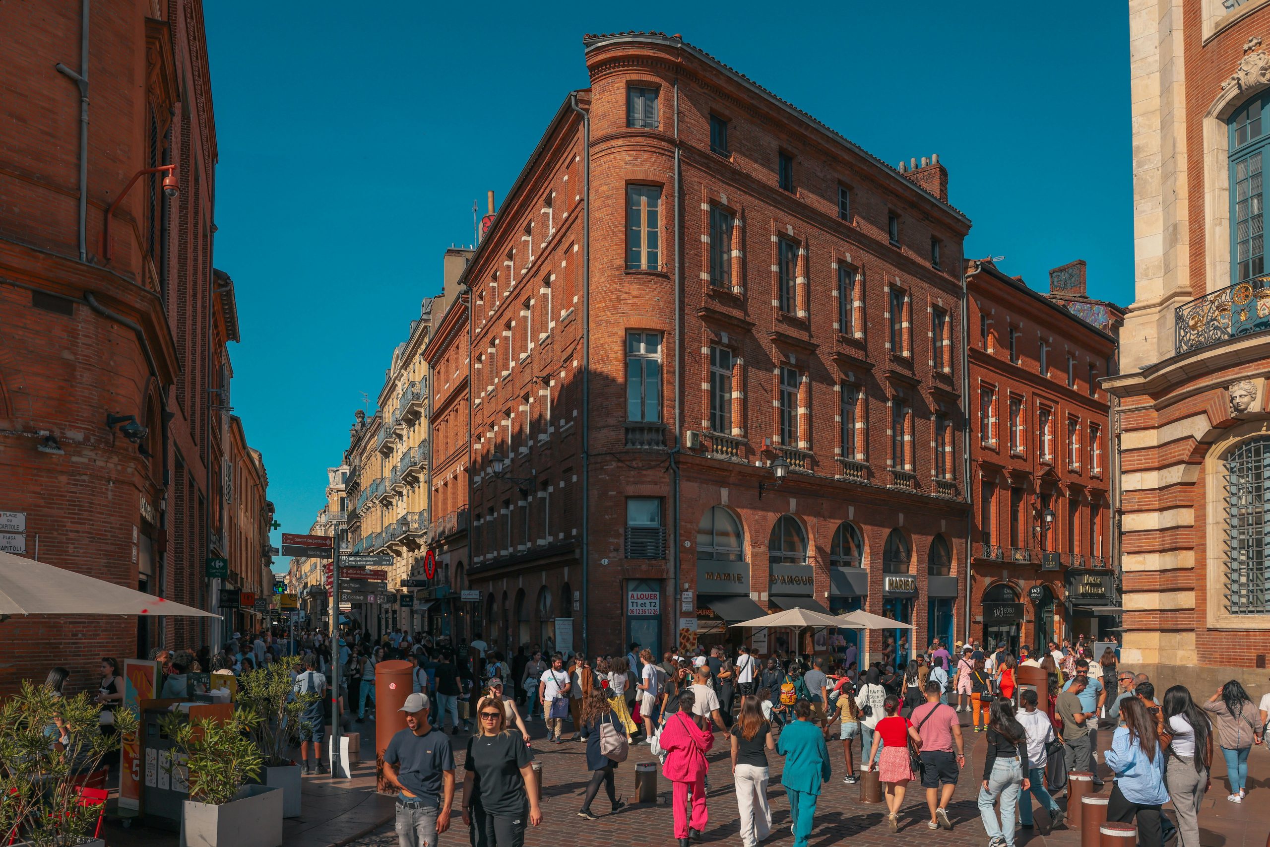 Crowds walking through the lively red-brick streets of central Toulouse on a sunny afternoon