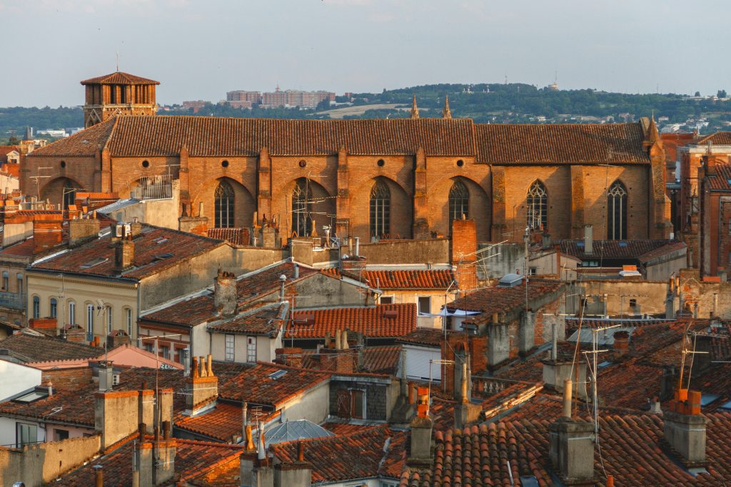 Sunlit rooftops and the Jacobins Convent in Toulouse’s historic center, captured during golden hour